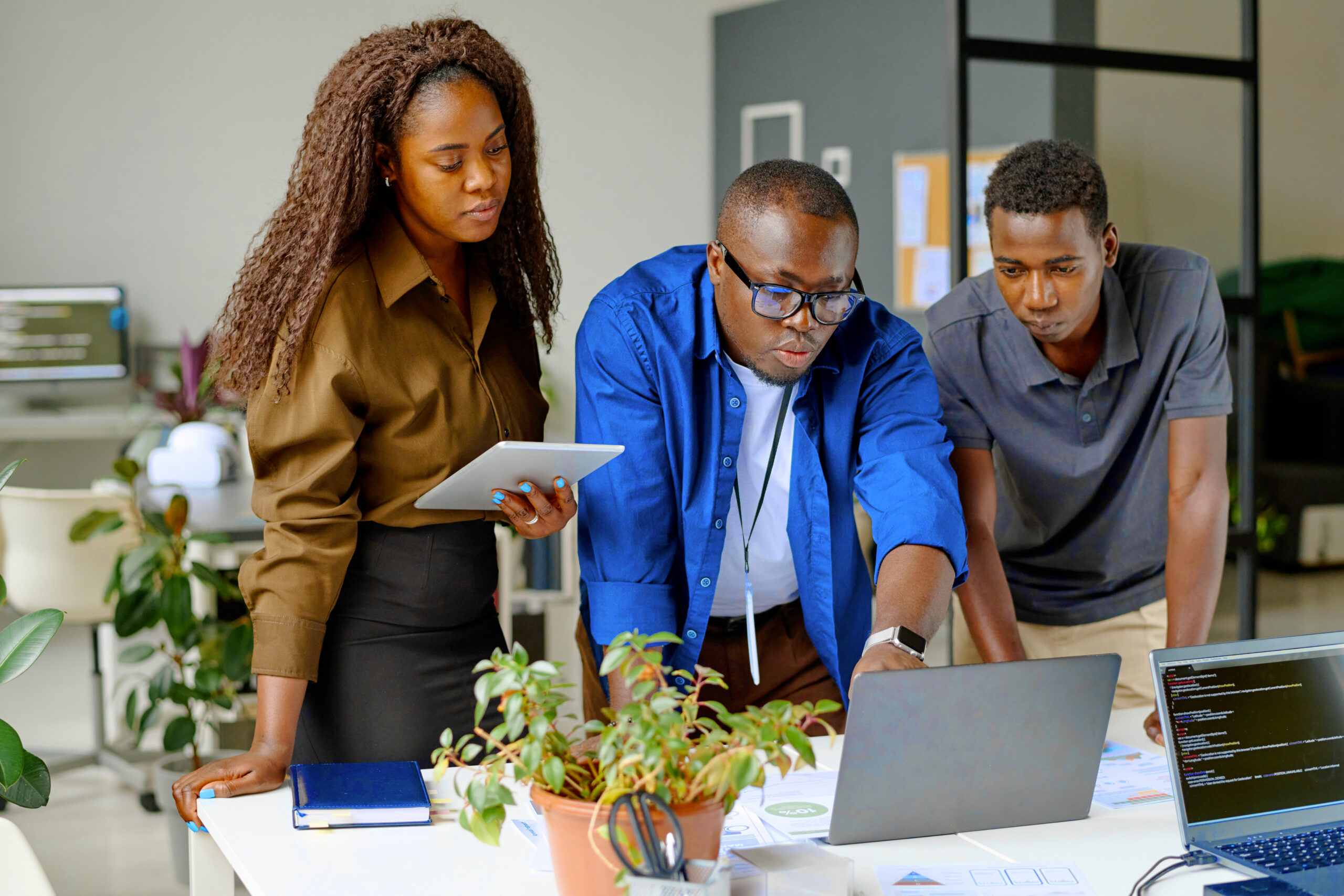 young african american teamlead surrounded by his subordinates pointing laptops screen